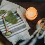 A serene spa setup featuring a jade roller, gua sha, towel, and candle for ultimate relaxation.
